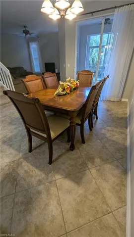 Dining space with a ceiling fan, a chandelier, and light tile patterned floors