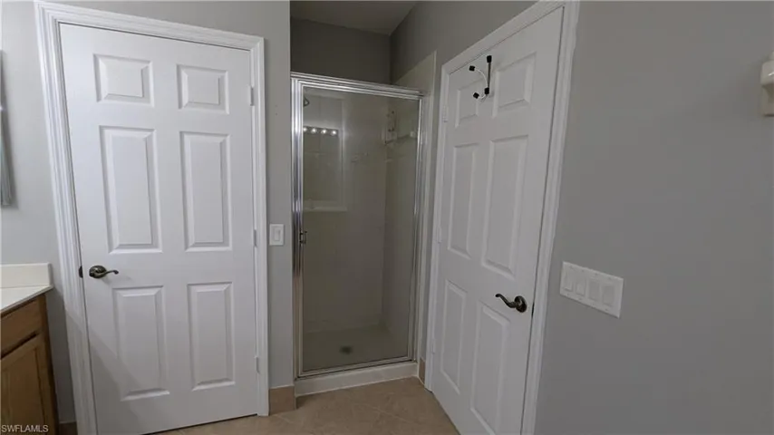 Full bath featuring light tile patterned floors, vanity, and a stall shower