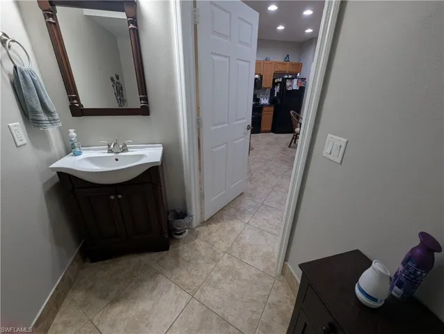 Bathroom featuring vanity, light tile patterned flooring, a textured wall, and recessed lighting