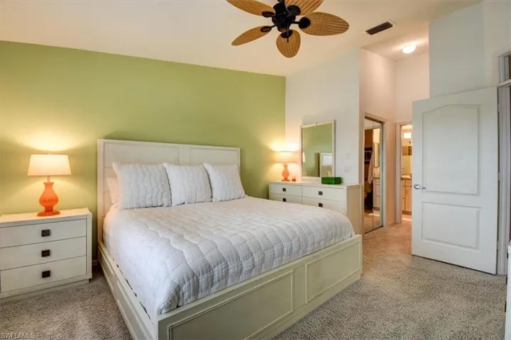 Bedroom with a closet, light carpet, and a ceiling fan
