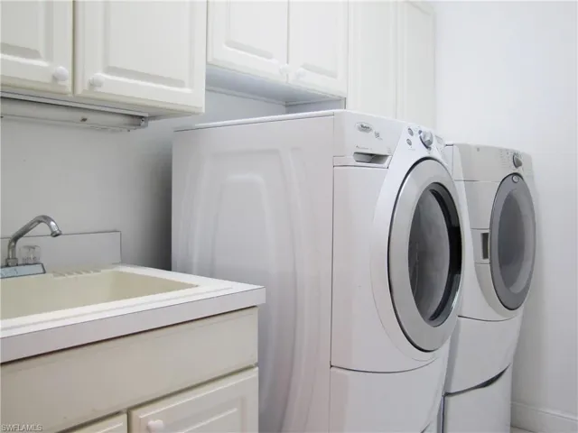 Washroom featuring cabinet space with HE front-load washer and dryer