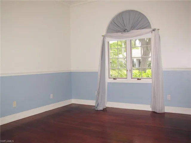 Bedroom with wood finished floors, baseboards, and crown molding