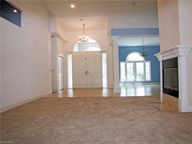 Living room with high ceiling, fireplace and recessed lighting.
