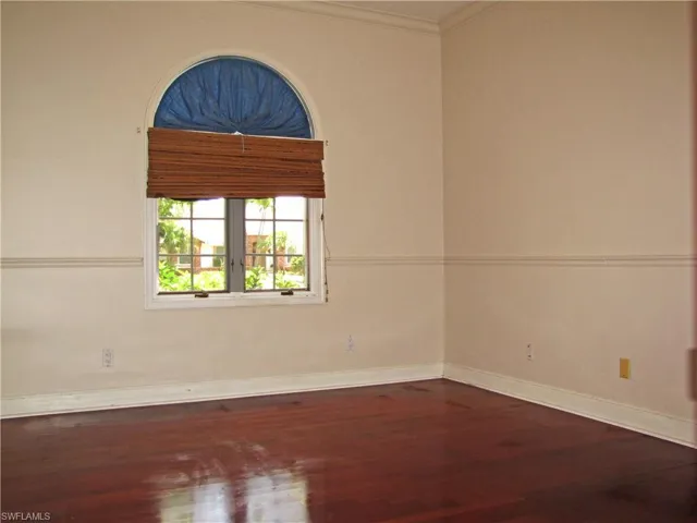 Bedroom featuring dark wood finished floors, ornamental molding, and baseboards