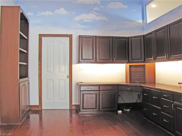 Office with dark wood cabinets and flooring.