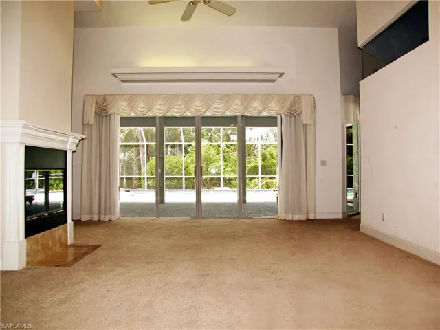 Living room with high ceiling, upgraded fireplace and beautiful landscaped view.