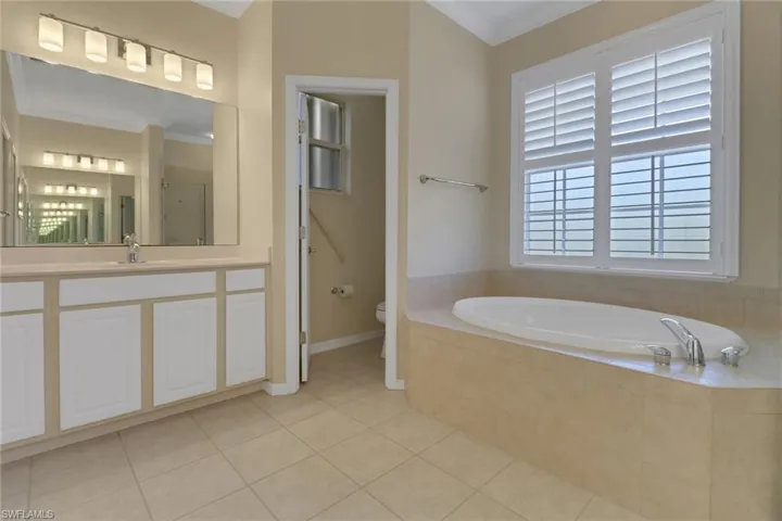 Full bathroom with a bath, tile patterned floors, a stall shower, toilet, and ornamental molding
