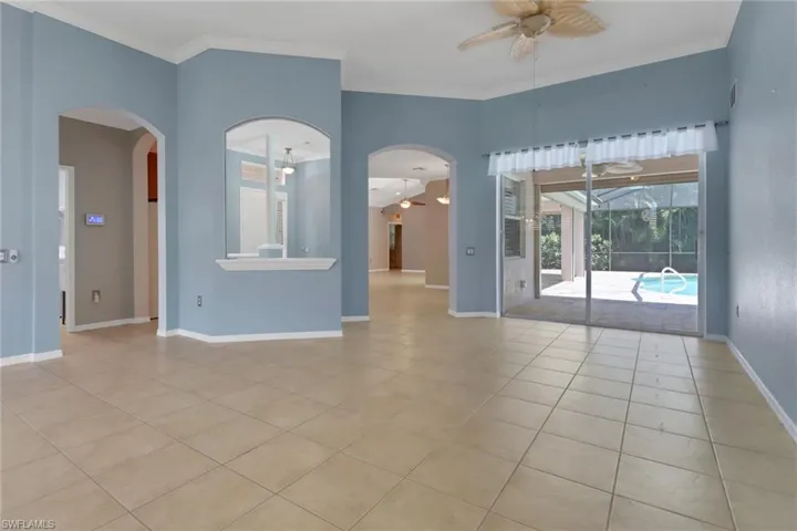 Empty room featuring ceiling fan, arched walkways, baseboards, and light tile patterned floors