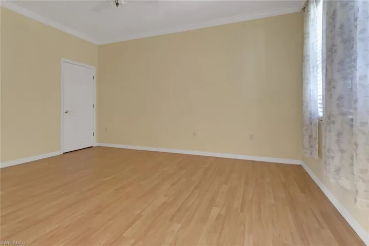 Spare room with ceiling fan, baseboards, crown molding, and light wood-style floors