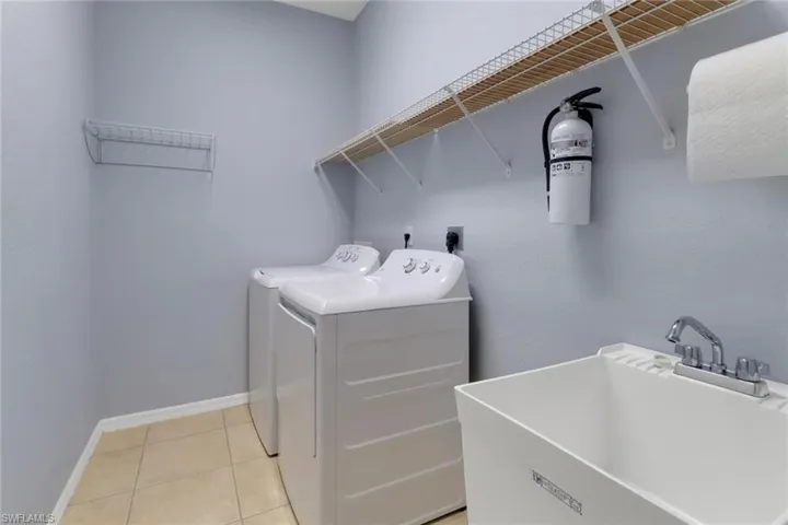 Washroom with laundry area, a sink, light tile patterned flooring, baseboards, and separate washer and dryer