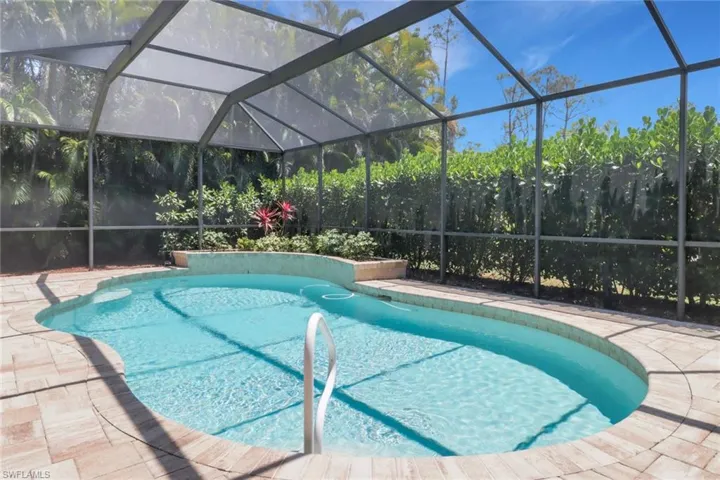 Outdoor pool with a patio area and glass enclosure