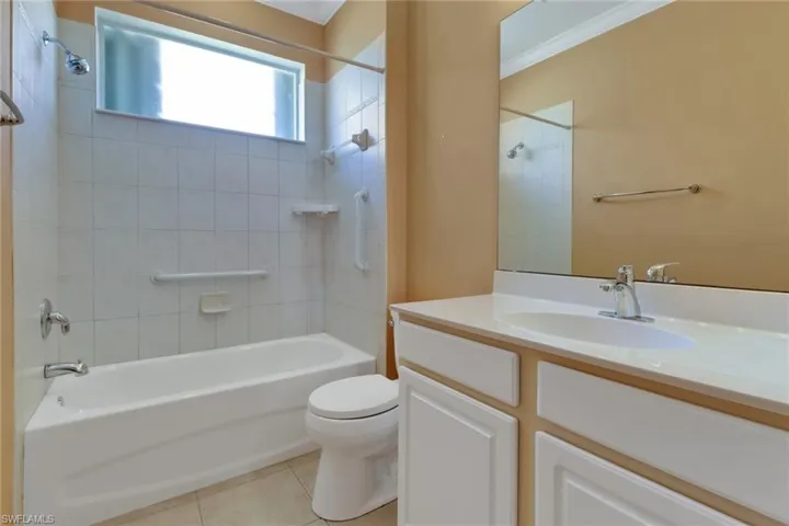 Bathroom with tile patterned flooring, toilet, vanity, ornamental molding, and shower / tub combination