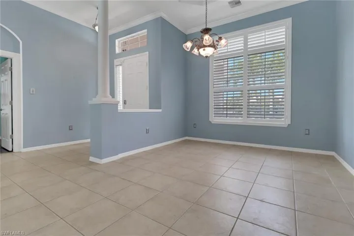 Unfurnished dining area featuring baseboards, crown molding, tile patterned flooring, and a chandelier