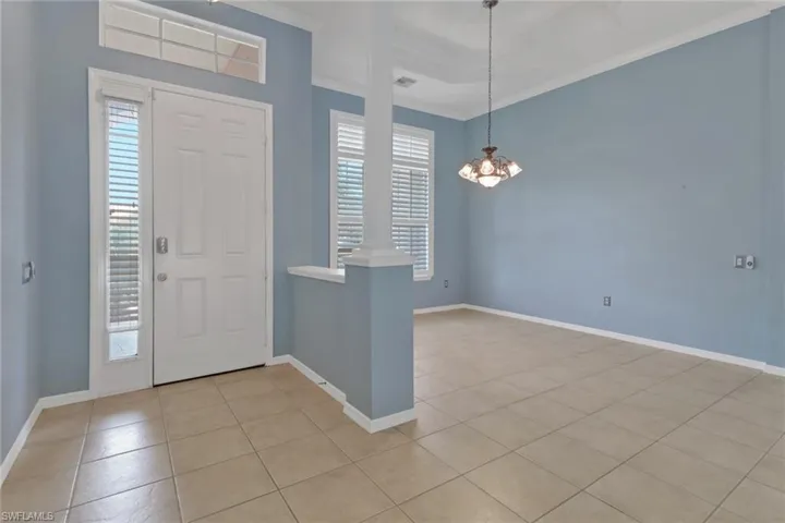 Foyer entrance featuring baseboards, an inviting chandelier, light tile patterned floors, and crown molding