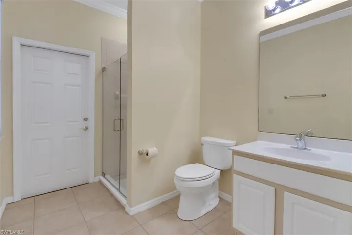 Bathroom featuring baseboards, tile patterned flooring, ornamental molding, and a stall shower