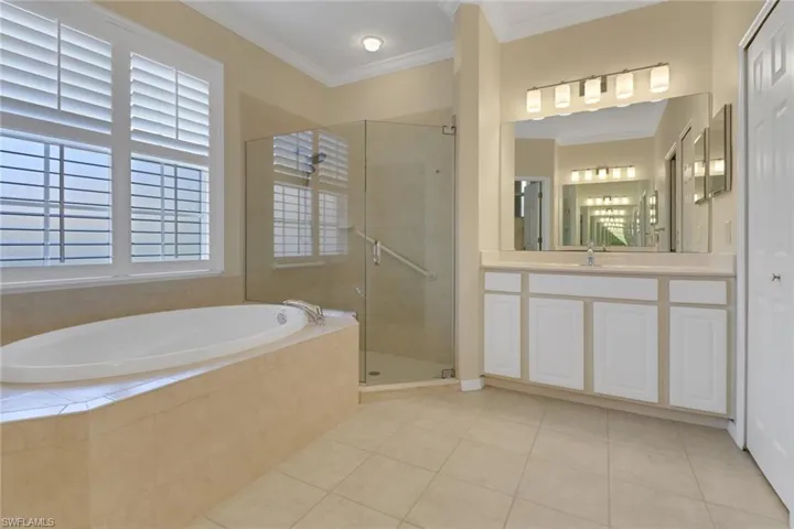 Bathroom featuring tile patterned flooring, a shower stall, a garden tub, vanity, and ornamental molding