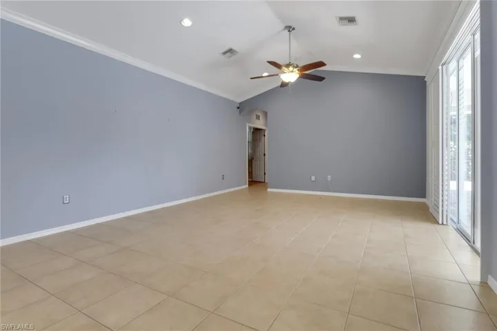 Empty room featuring ornamentalq molding, vaulted ceiling, a ceiling fan, and visible vents