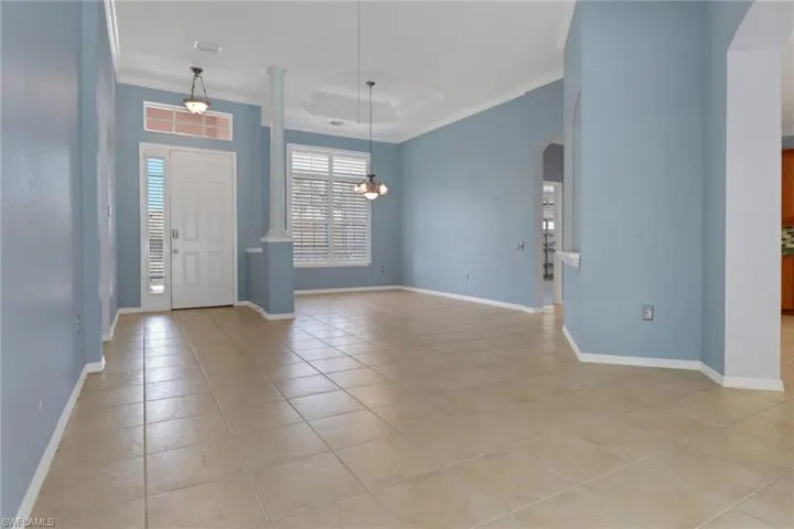 Foyer featuring arched walkways, light tile patterned flooring, baseboards, an inviting chandelier, and ornamental molding