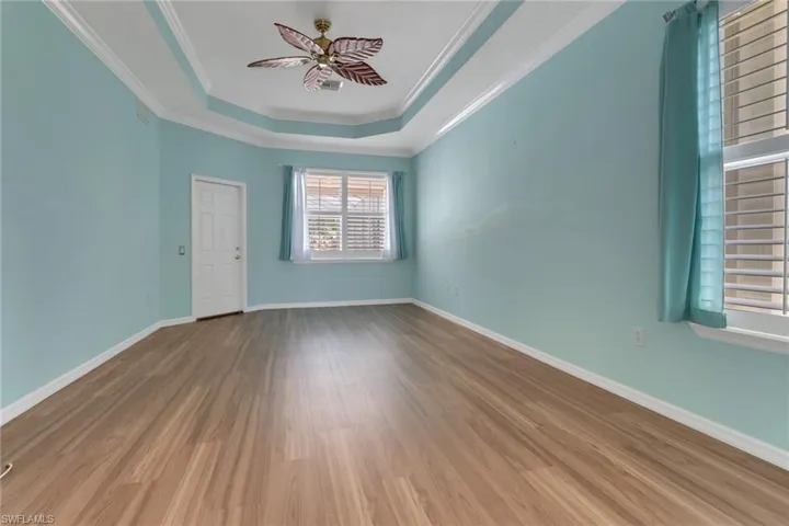 Spare room with ceiling fan, baseboards, wood finished floors, and a tray ceiling
