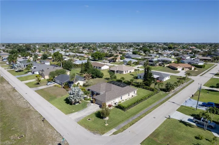 Aerial neighborhood perspective showcasing residential properties with varied rooflines and a mix of mature and nascent landscaping