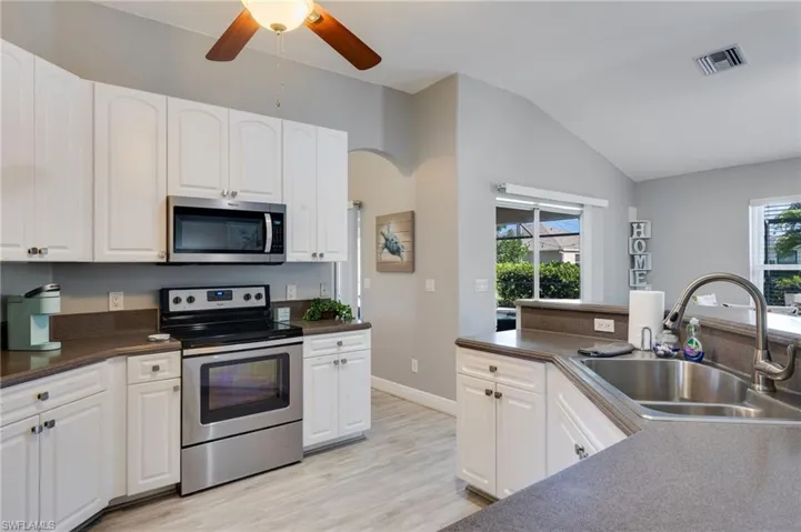 Kitchen featuring white cabinetry, stainless steel appliances, a double basin sink, and wood-finish flooring