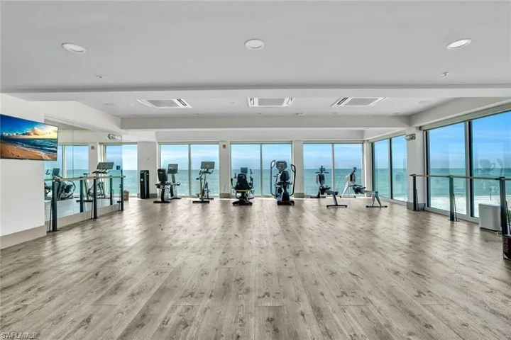 Gym with visible vents, a water view, and wood finished floors