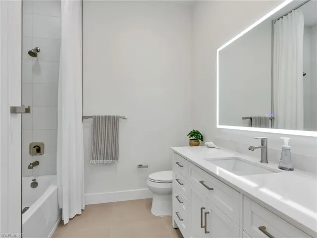 Full bath with light tile patterned flooring, shower / bath combo, and vanity