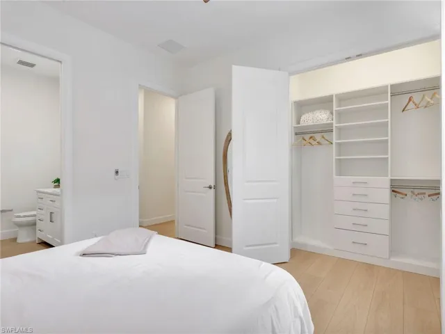 Bedroom with a closet, light wood finished floors, and ensuite bath