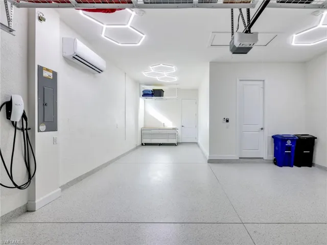 Garage featuring electric panel, a wall unit AC, a garage door opener, and car charger