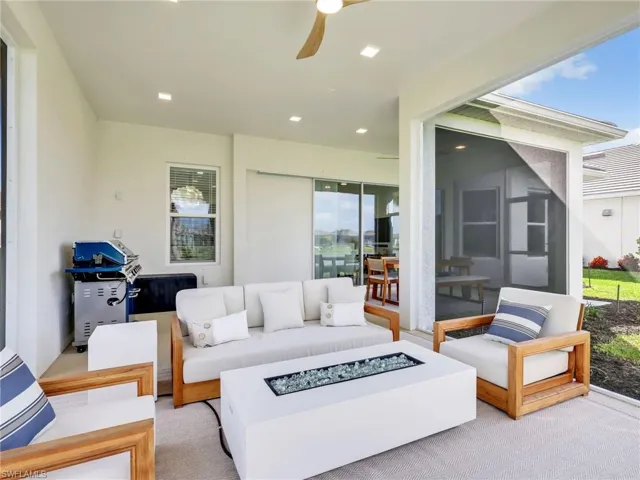 View of patio featuring an outdoor living space with a fire pit, a sunroom, and a ceiling fan