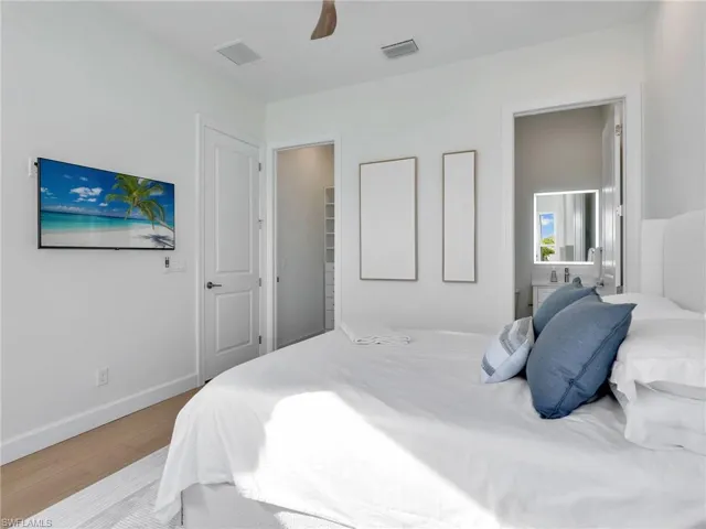 Bedroom featuring wood finished floors, a ceiling fan, and connected bathroom