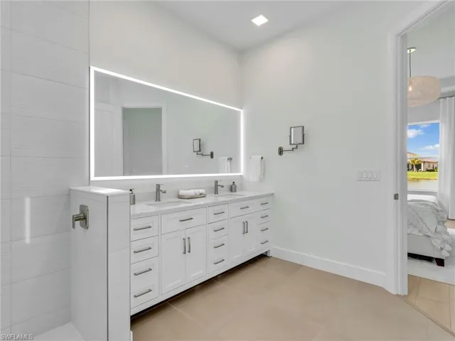 Ensuite bathroom featuring double vanity and light tile patterned floors