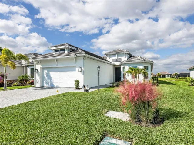 View of front of house with a front yard, stucco siding, decorative driveway, and an attached garage