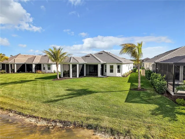 Back of house featuring a sunroom, a yard, a water view, a tiled roof, and a lanai