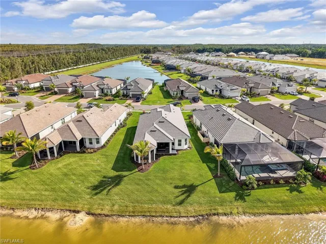 Aerial perspective of suburban area with a nearby body of water and a tree filled landscape