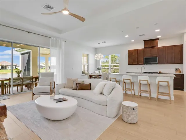 Living area with light wood-style floors, a ceiling fan, recessed lighting, a chandelier, and a water view