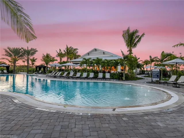 Pool at dusk featuring a community pool and a patio area