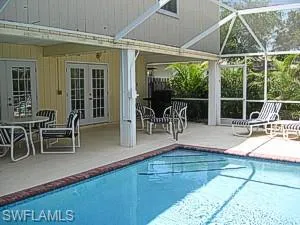 View of swimming pool featuring a patio, glass enclosure, and french doors