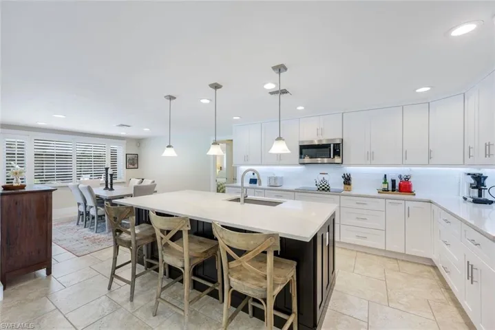 Kitchen with stainless steel microwave, a sink, black electric stovetop, backsplash, and recessed lighting