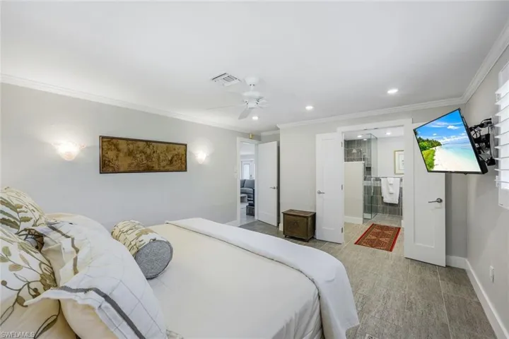 Bedroom with baseboards, crown molding, recessed lighting, ceiling fan, and ensuite bath