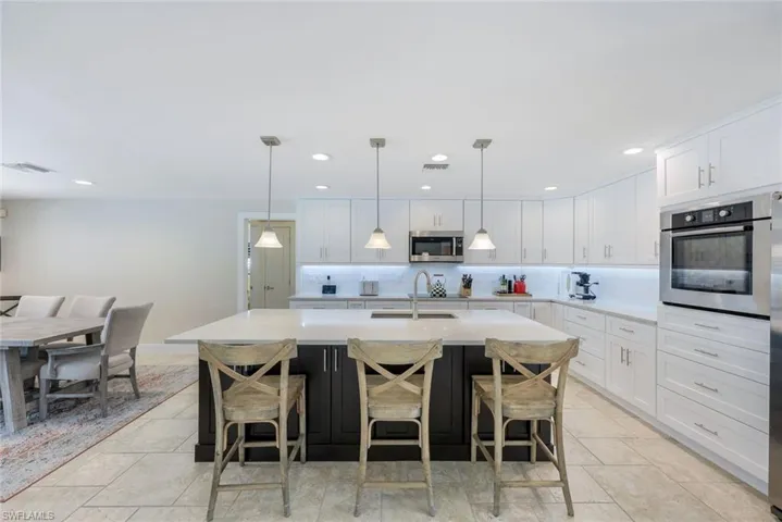 Kitchen featuring appliances with stainless steel finishes, light countertops, a sink, white cabinetry, and recessed lighting