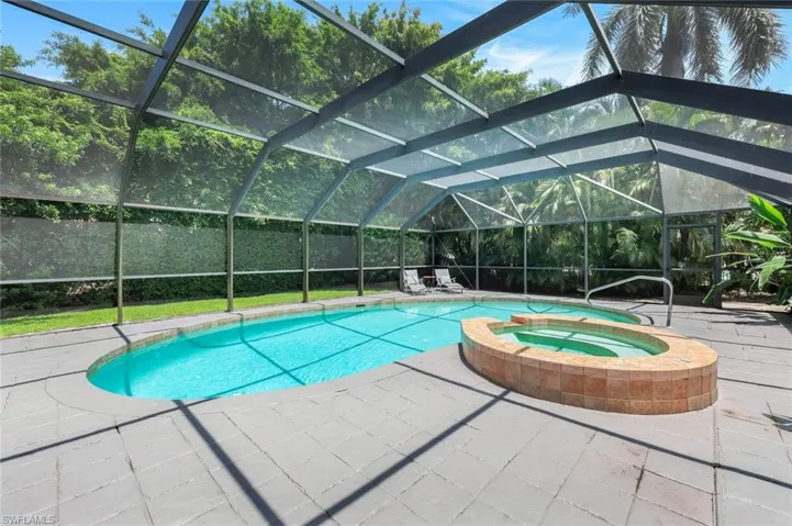 View of swimming pool featuring a patio, a pool with connected hot tub, and a lanai