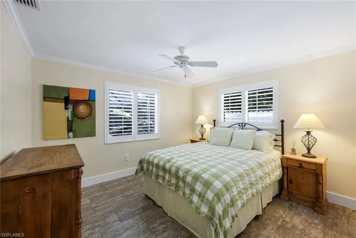 Bedroom featuring baseboards, crown molding, and a ceiling fan
