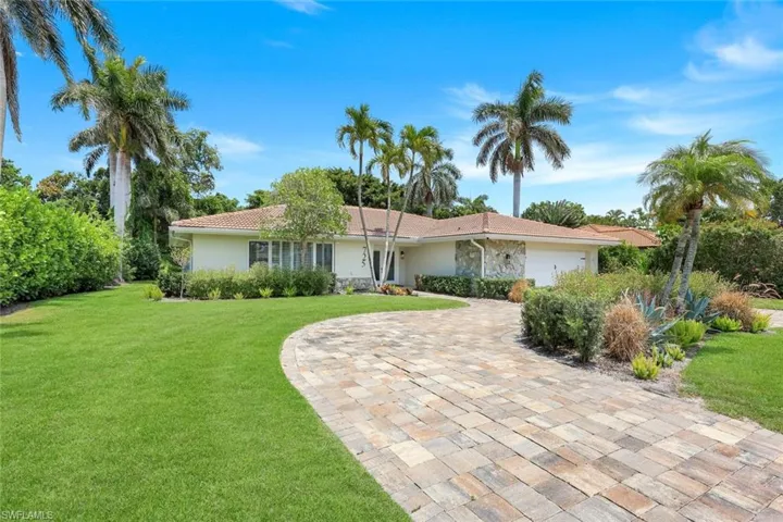 Single story home with stucco siding, an attached garage, driveway, and a front lawn