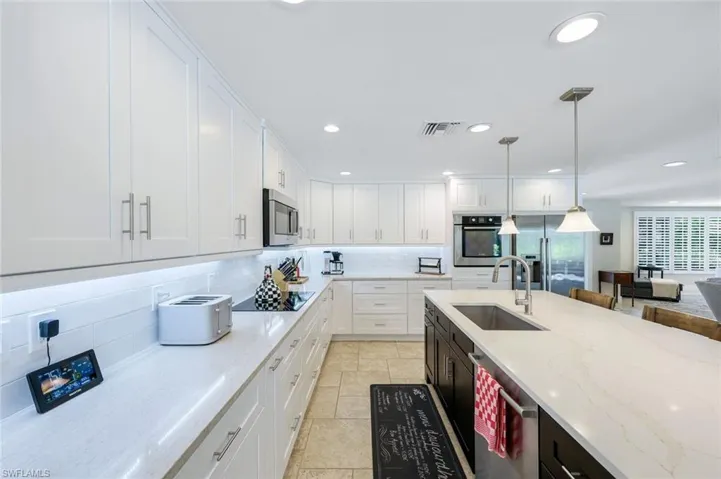 Kitchen featuring a sink, appliances with stainless steel finishes, backsplash, white cabinetry, and recessed lighting