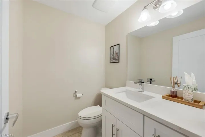 Half bathroom featuring vanity, toilet, baseboards, and tile patterned floors