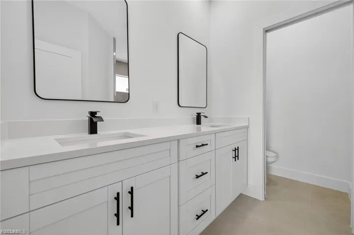 Dual vanity with white cabinetry and integrated sinks, complemented by matte black faucets and hardware