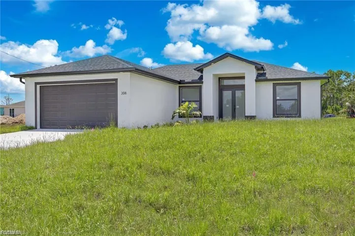 Contemporary stucco exterior with dark trim accents, a two-car garage, and a covered entry