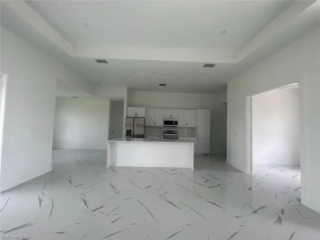 Kitchen featuring a tray ceiling, light tile floors, white cabinetry, and appliances with stainless steel finishes