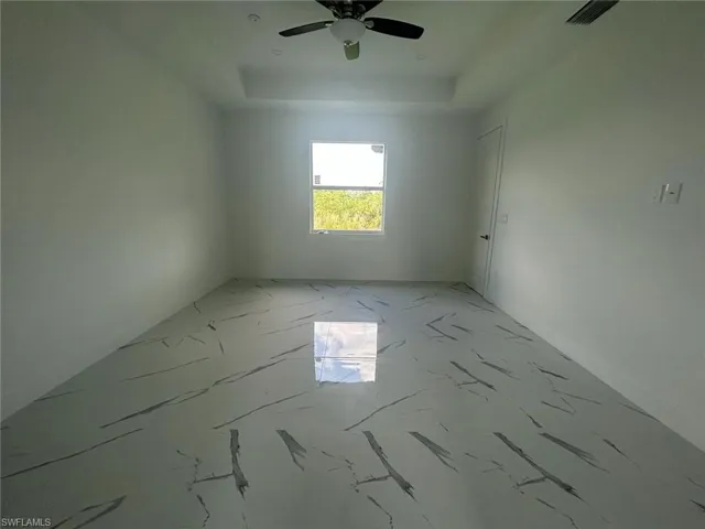 Empty room featuring tile flooring, ceiling fan, and a raised ceiling
